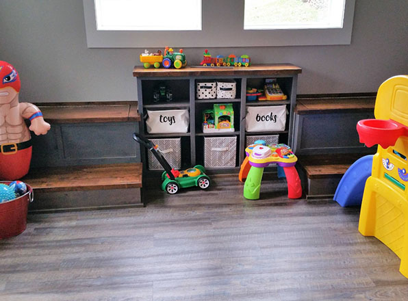 Toy shleves and bins built into wall under windows. Basement Remodeling. Johnson County Remodeling.