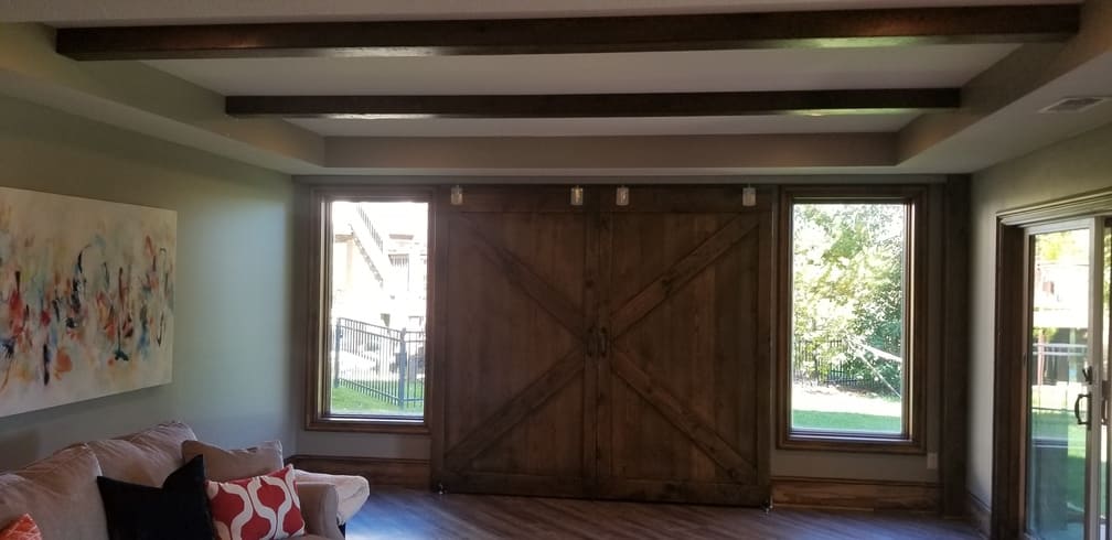 Barn doors closed in front of large screen tv. Windows exposed. Basement Remodeling. Johnson County Remodeling.